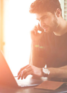 man on phone looking at computer