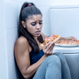 woman eating pizza in bathroom