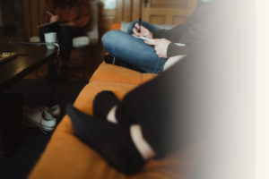 two people sitting on a couch writing faded