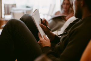 man writing in journal and talking