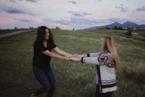 Two girls holding hands and spinning outside