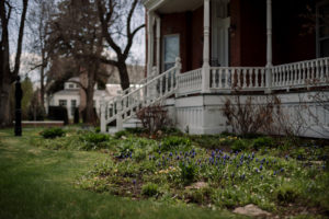 White porch wrapped around brick house