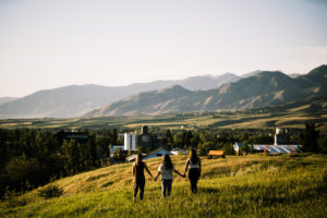 Girls walking through grass with a mountain background